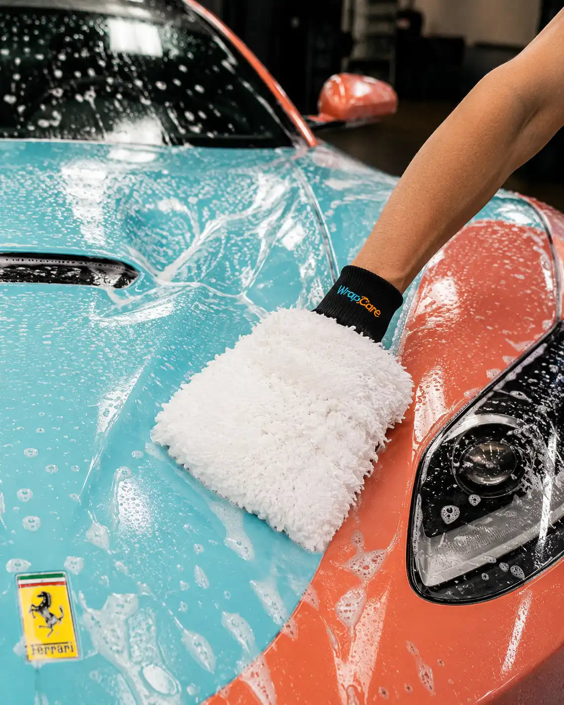 Der WrapCare Waschhandschuh White Günther seift einen Mercedes CLA AMG mit bunter Folie ein.